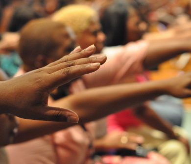 African American hands reach out in prayer during a praise and worship moment